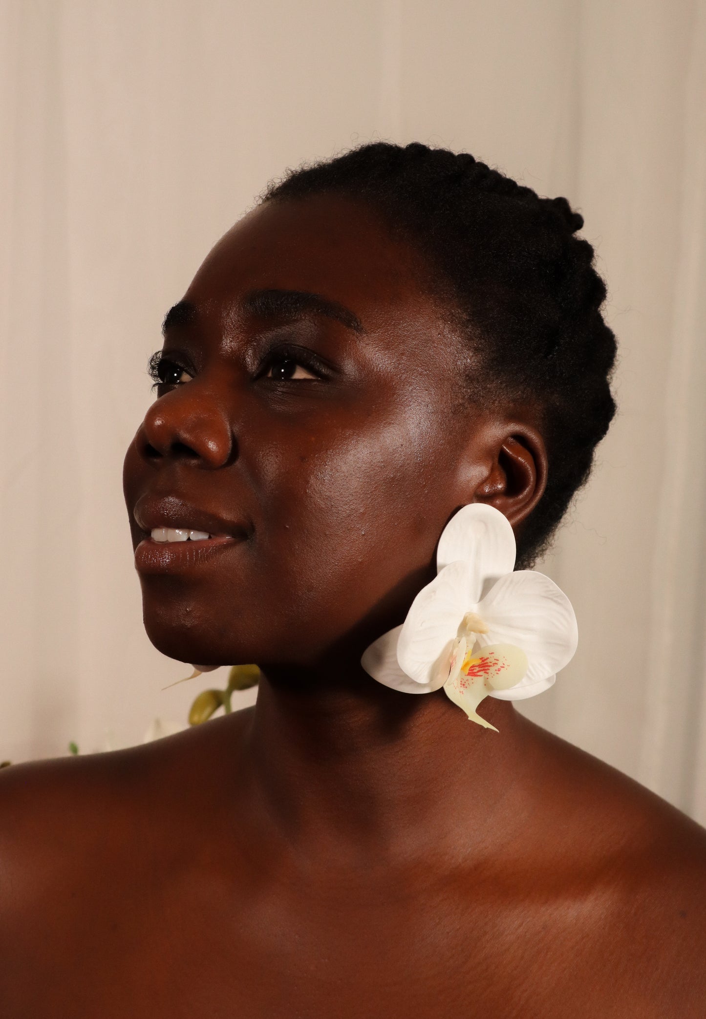 Woman with a white orchid earring against a neutral background