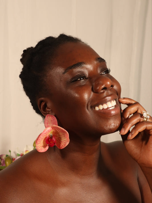 Person with a flower in their ear against a plain background