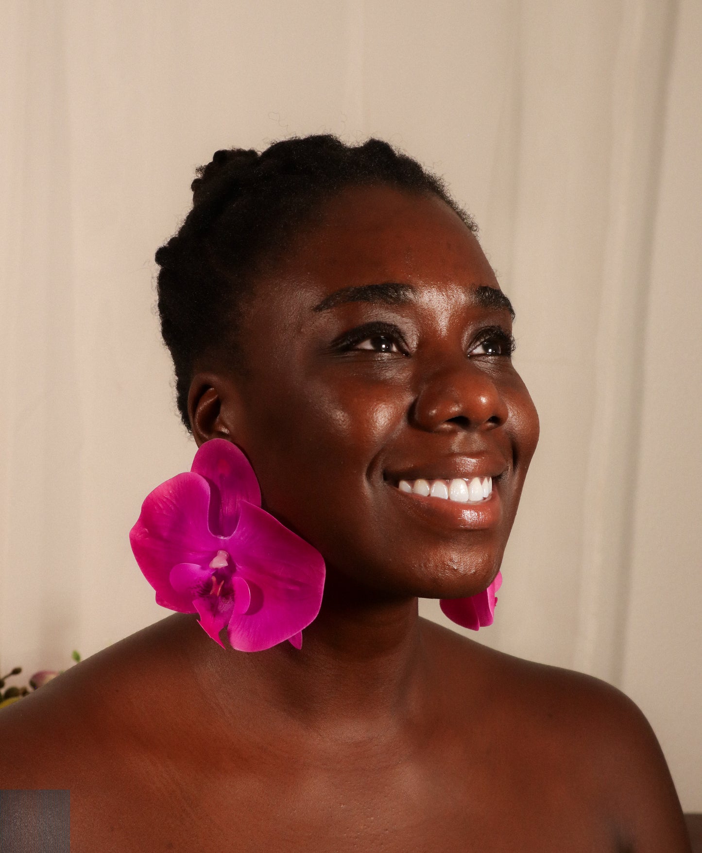 Woman with a violet orchid in her hair against a beige background